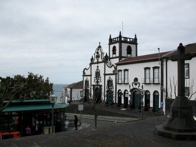 Eine malerische Straße in Ponta Delgada, umgeben von historischen Gebäuden und einem Blick auf das Meer im Hintergrund.