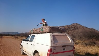 Ein Junge sitzt einem Jeep mit Dachzelt - Namibia mit Kindern
