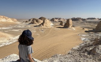 Kind sitzt auf der Weißen Wüste und genießt den Ausblick - Ägypten Reise mit Kindern