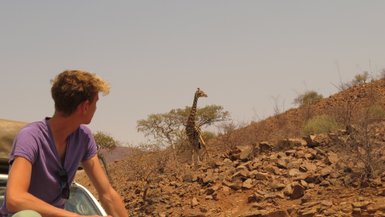 Ein Junge beobachtet gespannt eine Giraffe - Namibia mit Jugendlichen