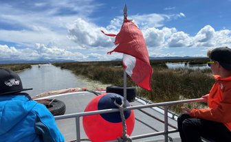 Zwei Kinder sitzen auf einem Boot, während sie die ruhige Wasserlandschaft des Titicaca-Sees genießen.