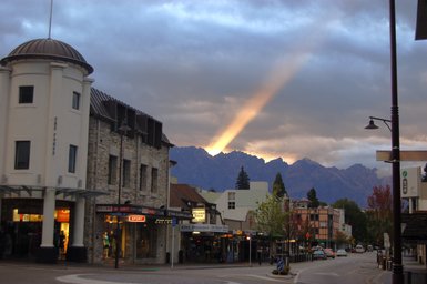 Die Stadtansicht von Queenstown zeigt eine belebte Straße mit Geschäften und beeindruckenden Bergen im Hintergrund.