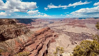 Der Blick auf den Grand Canyon zeigt beeindruckende, schichtartige Felsformationen unter einem strahlend blauen Himmel.