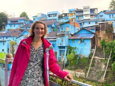 Frau steht vor den markanten blauen Häusern im Dorf – Bali Reise mit Kindern