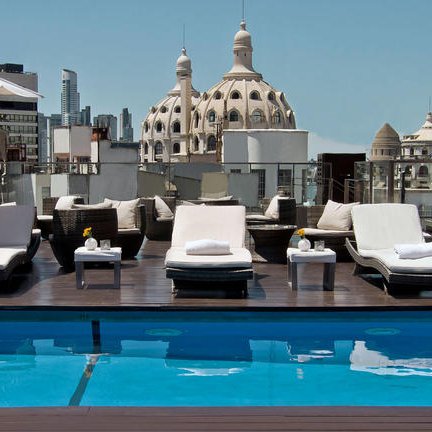 Ein luxuriöser Poolbereich auf dem Dach mit Liegen und Blick auf die beeindruckende Architektur von Buenos Aires.