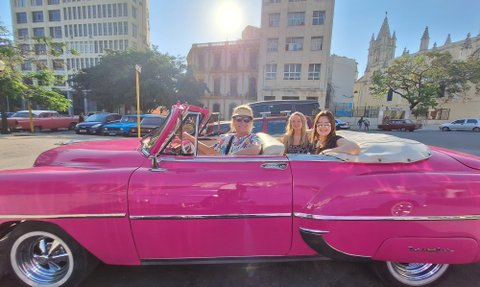 Drei Frauen sitzen in einem pinken Oldtimer-Cabrio in Havanna - Kuba mit Kindern