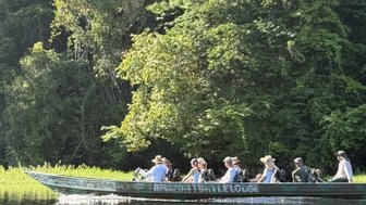 Eine Gruppe von Menschen sitzt in einem Boot und genießt die Zeit auf einem ruhigen Gewässer umgeben von dichtem Grün.