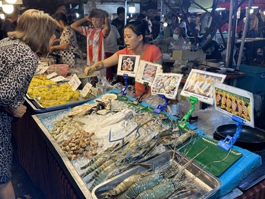 Frau betrachtet die Auslage auf einem Markt - Thailand Familienreise