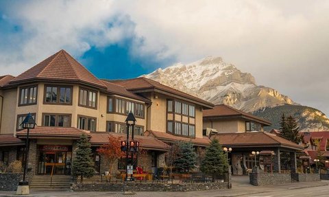 Das Elk Avenue Hotel präsentiert sich mit einer charmanten Fassade und Blick auf majestätische Berge im Hintergrund.