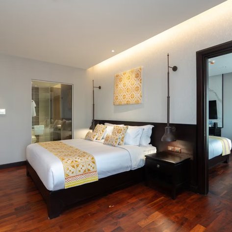 Ein modernes Hotelzimmer mit einem großen Bett, dekoriert mit gelben Akzenten und einem eleganten Holzfußboden.