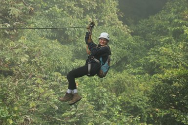 Frau schwebt lachend an einer Zipline durch die Baumkronen des Selvatura Parks – Costa Rica Reise mit Kindern