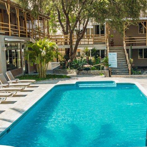 Ein einladender Poolbereich mit Liegen, umgeben von üppigem Grün und modernen Gebäuden, ideal für Entspannung.