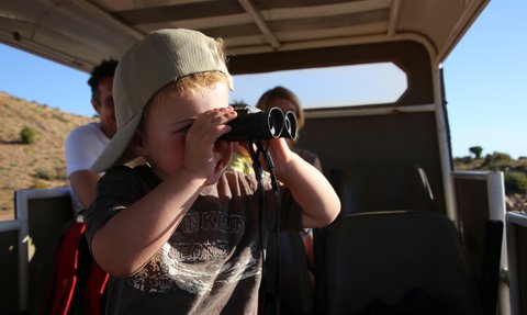 Kind beobachtet mit einem Fernglas während einer Safari – Südafrika Reise mit Kindern