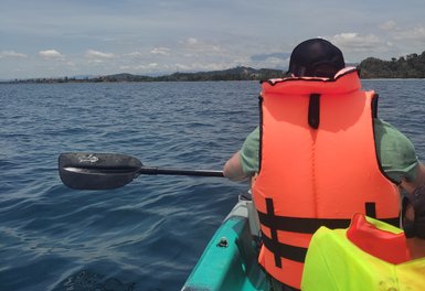 Vater paddelt im Kajak entlang der Küste beim Nexus Resort – Malaysia & Borneo mit Kindern