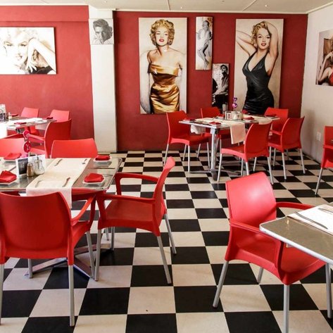 Ein stilvolles Restaurant mit roten Stühlen und einem Schachbrettboden, geschmückt mit Bildern von Marilyn Monroe.