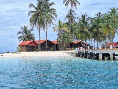 Ein malerischer Strand mit Palmen und roten Dächern, die sich harmonisch in die tropische Landschaft einfügen.