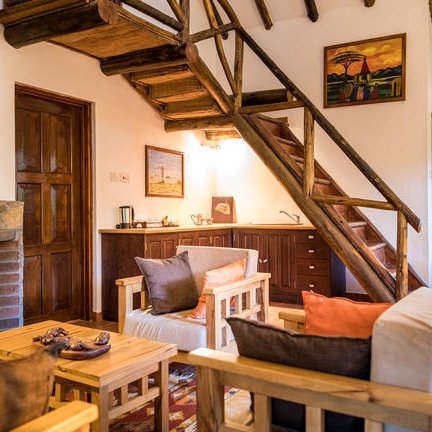 Ein gemütlicher Wohnraum mit Holztreppe, bequemen Möbeln und einem Kamin, der eine einladende Atmosphäre schafft.