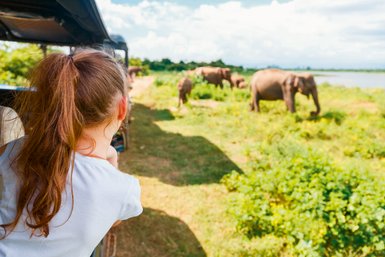 Ein Mädchen erlebt die Safari im Udawalawe Nationalpark aus dem offenen Jeep hautnah – Sri Lanka Reise mit Kindern