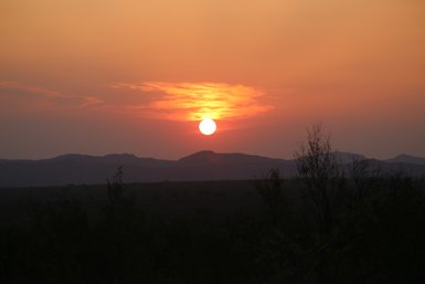 Die untergehende Sonne taucht die Savanne im Kruger Nationalpark in warmes Licht – Südafrika Reise mit Kindern