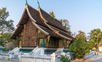 Ein prächtiger Tempel mit kunstvoll verzierten Wänden und einem geschwungenen Dach, umgeben von üppigem Grün.