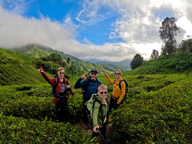 Familie hält einen Moment mit einem Selfie vor der grünen Landschaft der Cameron Highlands fest – Malaysia & Borneo mit Kindern