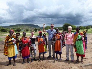 Eine Gruppe von Maasai-Kriegern und Touristen posiert fröhlich vor einer beeindruckenden Landschaft mit dunklen Wolken.