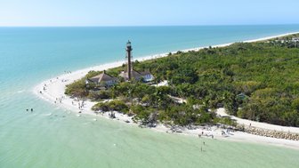 Ein malerischer Blick auf Sanibel Island mit einem Leuchtturm, umgeben von üppigem Grün und einem klaren blauen Wasser.
