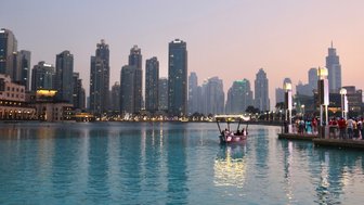 Eine traditionelle Dhow fährt sanft über das ruhige Wasser des Dubai Creeks, umgeben von beeindruckenden Wolkenkratzern.