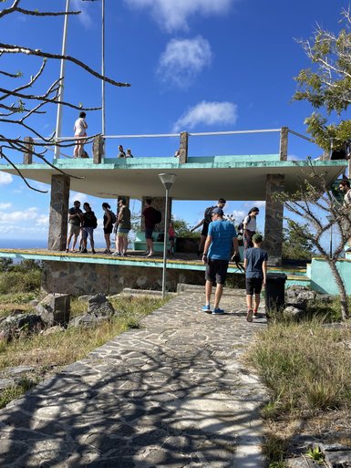 Eine Gruppe von Menschen steht auf einer Aussichtsplattform mit Blick auf die Landschaft und den blauen Himmel.
