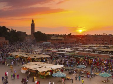 Djemaa el Fna Platz mit Menschen und Marktständen im Licht des Sonnenuntergangs in Marrakesch – Marokko Reise mit Kindern