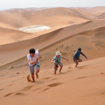 Drei Kinder laufen eine Düne hinauf - Namibia Rundreise mit Kindern