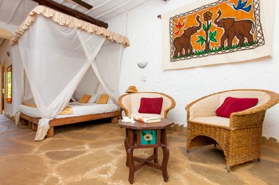 Ein gemütliches Zimmer mit einem Himmelbett, umgeben von einem Moskitonetz und einem rustikalen Holztisch.