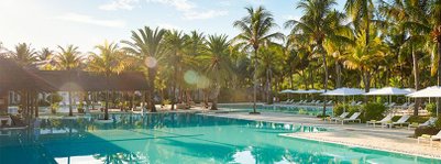 Ein glitzernder Pool umgeben von üppigen Palmen und Sonnenliegen, ideal für entspannende Tage in der Sonne.