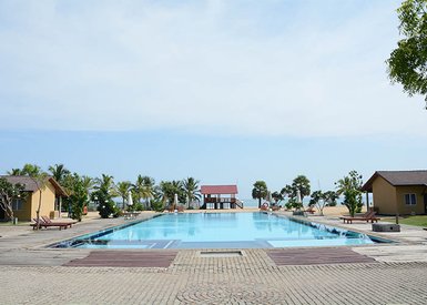 Ein weitläufiger Pool mit klarem Wasser, umgeben von Palmen und gemütlichen Liegen, bietet eine entspannende Urlaubsatmosphäre.