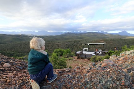 Kind blickt neugierig auf die Landschaft in der Buffelsdrift Game Lodge – Garden Route mit Kindern