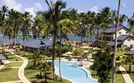 Ein tropisches Resort mit einem glitzernden Pool, umgeben von Palmen und Blick auf das Meer, ideal für Entspannung.