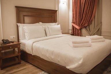 Ein elegantes Hotelzimmer mit einem großen Bett, weißen Kissen und frischen Handtüchern auf der Bettdecke.