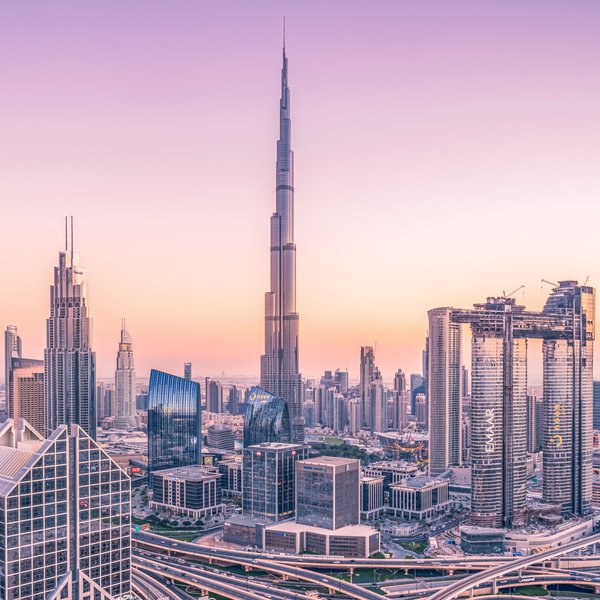 Die Skyline von Dubai erstrahlt in sanften Pastellfarben während der Dämmerung, mit dem Burj Khalifa als markantem Mittelpunkt.