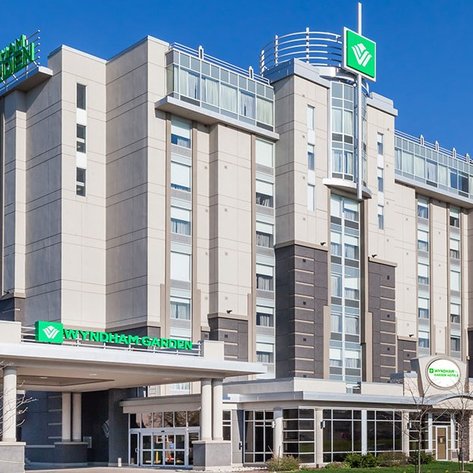 Das Wyndham Garden Hotel zeigt eine moderne Architektur mit großen Fenstern und einem klaren blauen Himmel im Hintergrund.