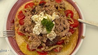 Ein großzügig belegtes Brot mit Thunfisch, frischen Tomaten, Zwiebeln und einer cremigen Schicht Mozzarella in der Mitte.