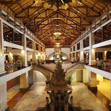 Der großzügige Lobbybereich des Nusa Dua Beach Hotels zeigt eine beeindruckende Holzdecke und elegante Möbel.