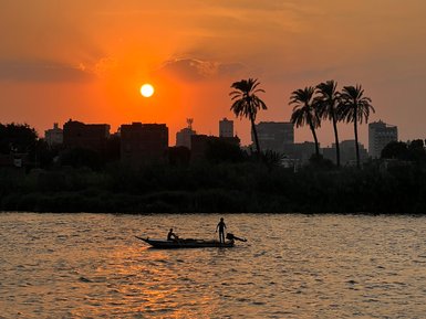Ein Boot fährt ruhig auf dem Nil während eines Sonnenuntergangs – Ägypten Reise mit Kindern