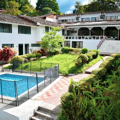 Ein einladender Außenbereich mit einem Pool, umgeben von gepflegten Gärten und einem charmanten Hotelgebäude im Hintergrund.