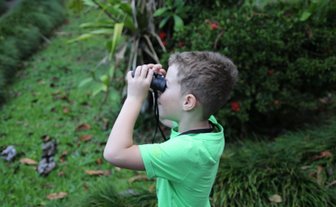 Junge beobachtet die Tierwelt mit Fernglas bei der Maquenque Eco Lodge im Sarapiquí-Tal – Costa Rica Reise mit Kindern