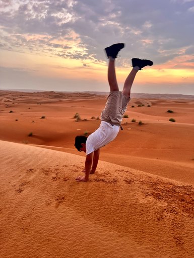 Junge macht Handstand in der Wahiba-Wüste beim Sonnenuntergang – Oman Reise mit Kindern