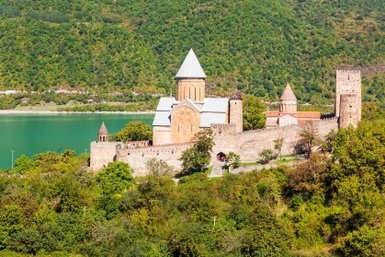 Die beeindruckende Ananuri-Festung thront majestätisch über dem smaragdgrünen Wasser des Stausees, umgeben von üppigem Grün.