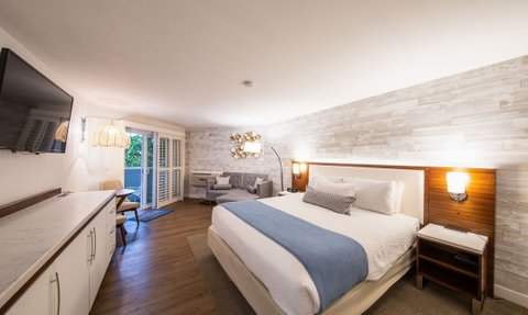 Ein modernes Hotelzimmer mit einem großen Bett, einem Fernseher und einem gemütlichen Sitzbereich, ideal für Entspannung.