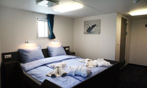 Ein gemütliches Schlafzimmer mit einem großen Bett, blauen Kissen und handtuchförmigen Dekorationen auf der Bettdecke.