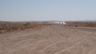 Ein Jeep fährt über eine unbefestigte Straße - Namibia Urlaub mit Kindern