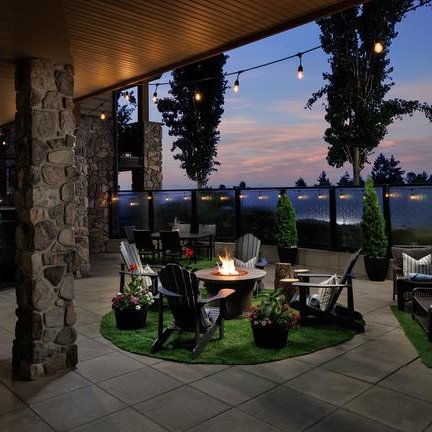 Eine gemütliche Terrasse mit einem Feuerplatz, umgeben von Pflanzen und Stühlen, ideal für entspannte Abende.